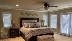 A bedroom with a large bed, a ceiling fan, and a window with blinds. - Relaxing Lake View Condo (Hot Springs)