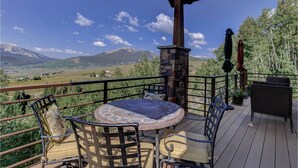 A wooden deck with a stone fireplace, outdoor furniture, and a scenic mountain view. - Amazing Mountain Home w/ 360 degree mountain views, hot tub and outdoor deck.   (Crested Butte)