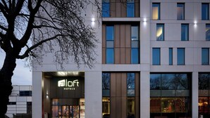 A modern hotel with a prominent 'aloft' sign, large windows, and a tree in the foreground. - Aloft by Marriott Birmingham Eastside (Birmingham)