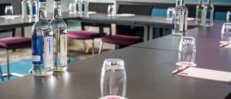 Et mødelokale med borde dækket med vandflasker, glas og navneskilte.