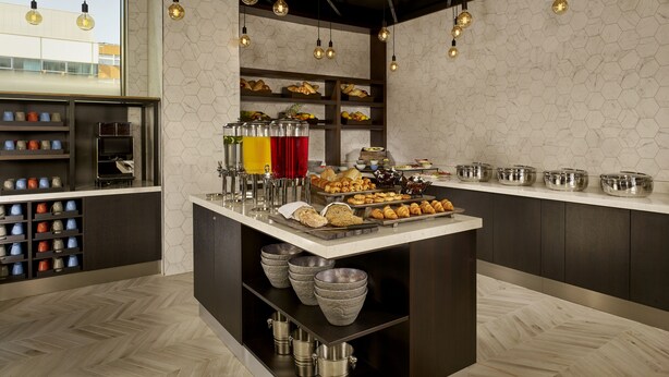 A modern kitchen with a central island, hexagonal patterned walls, and pendant lighting. - Aloft by Marriott Birmingham Eastside (Birmingham)