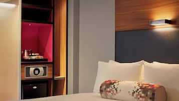 Une chambre d’hôtel équipée d’un lit, d’un oreiller, d’un coffre-fort numérique et d’un mini-bar.