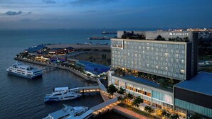 A waterfront Marriott hotel with multiple buildings, a marina with yachts, and a view of the ocean.