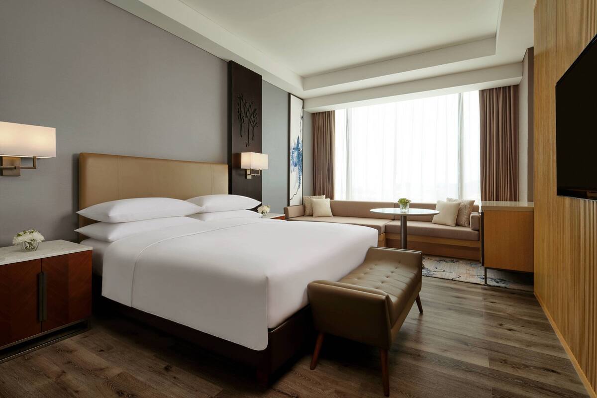 Una habitación de hotel con una cama grande, un sofá, una mesita y un televisor.