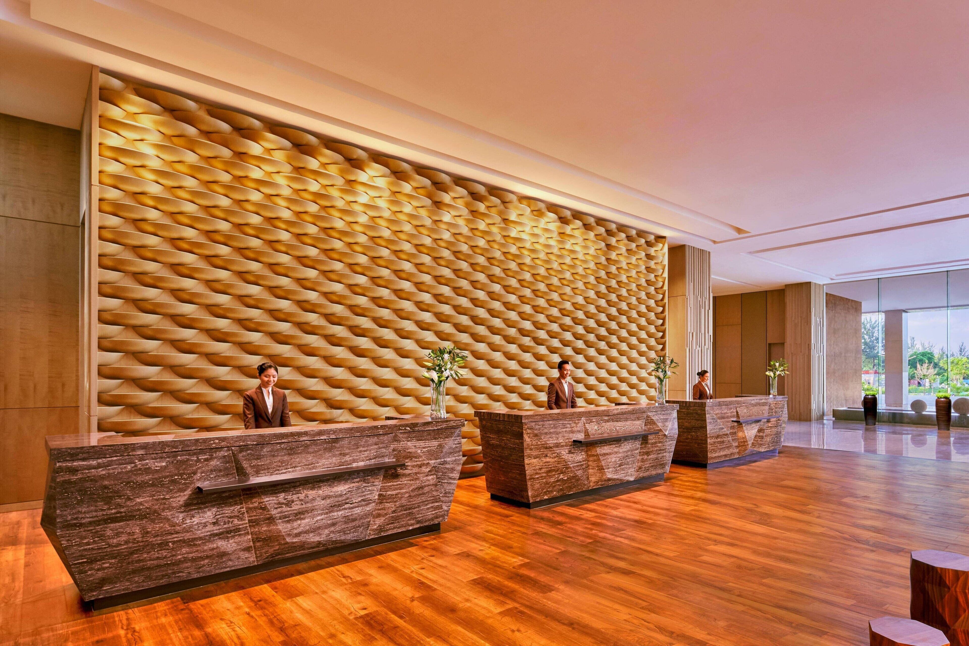 A reception area with wooden reception desks and a textured wall.