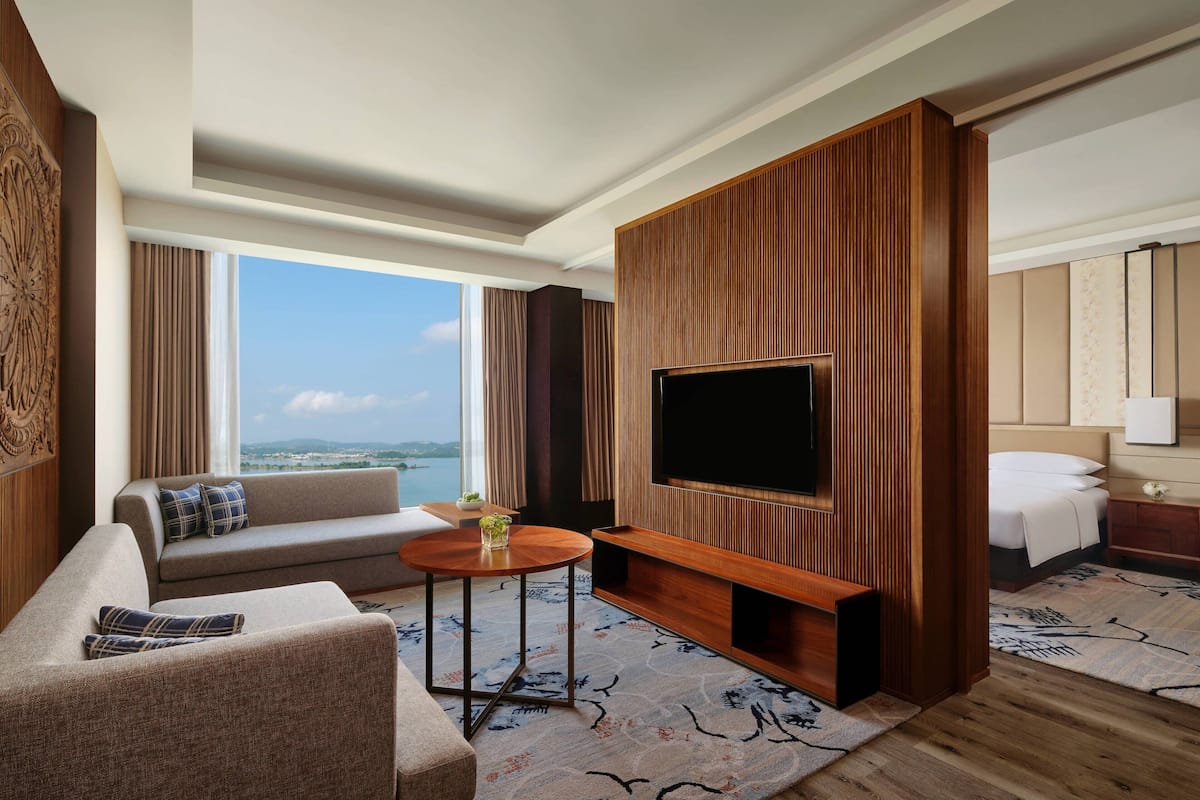 Una habitación de hotel moderna con un televisor grande, un sofá, una mesita y una cama.