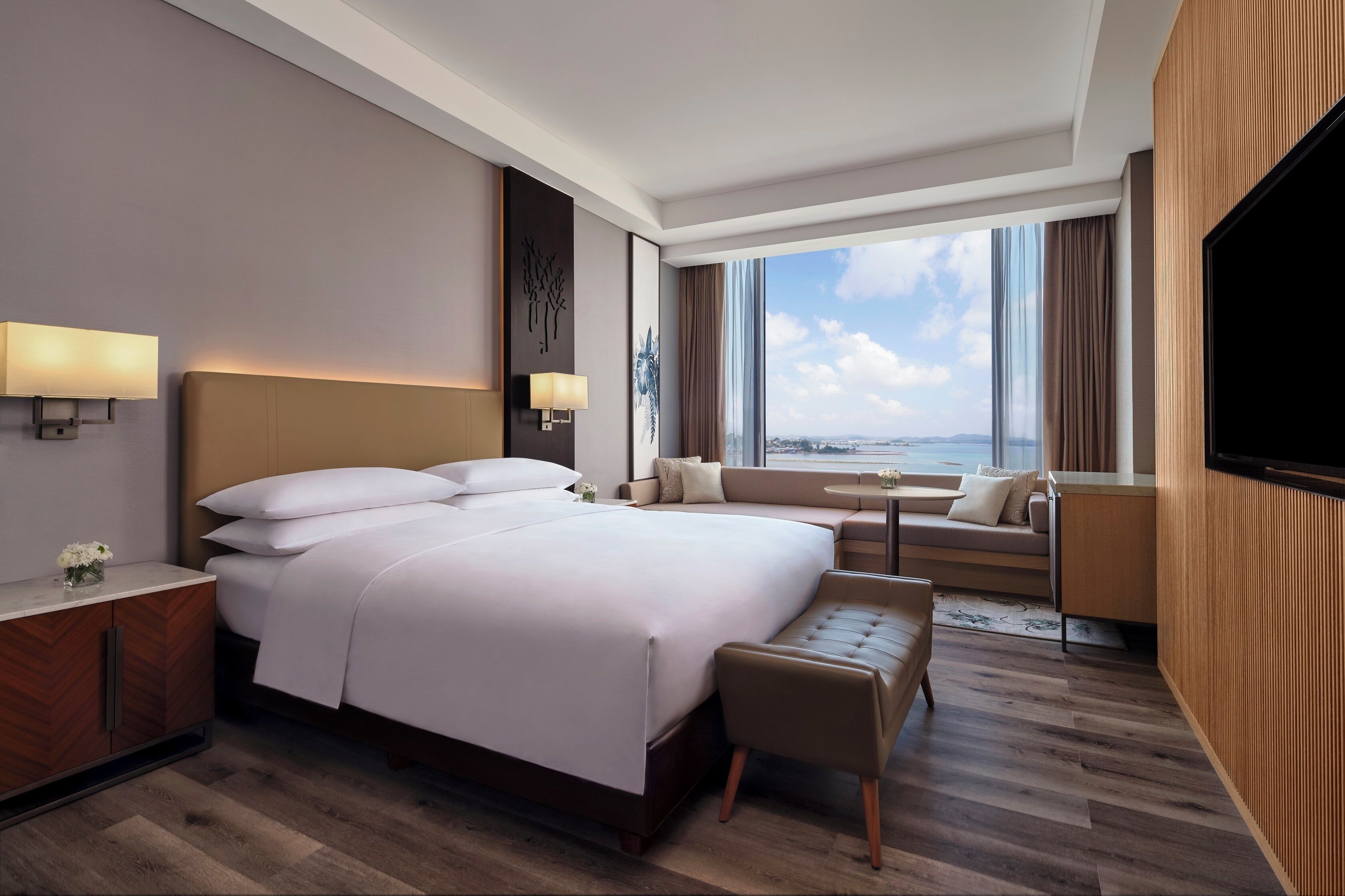 Una habitación de hotel moderna con una cama grande, un escritorio, un sofá y un televisor.