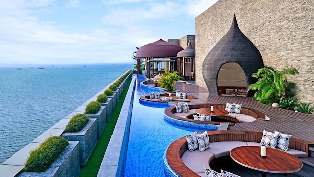 A luxurious outdoor pool area with tiered seating and a view of the sea.