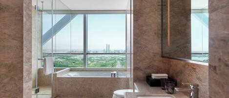 A modern bathroom with a large window, a bathtub, a toilet, and a sink.