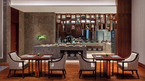 Un área de comedor moderna con una isla central, dos mesas auxiliares y cuatro sillas.