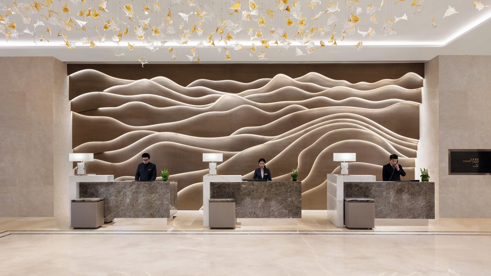 A reception area with three counters, each with a receptionist. The wall behind the counters features a textured, wavy design.