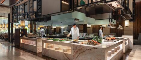 A spacious, modern kitchen with marble countertops, multiple serving stations, and a high ceiling with exposed beams.