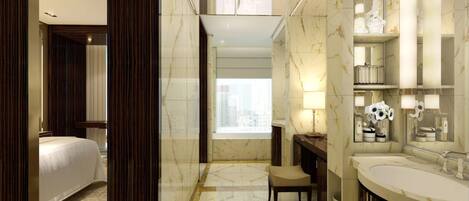 A modern hotel bathroom with a large mirror, two sinks, a vanity, and a chair.