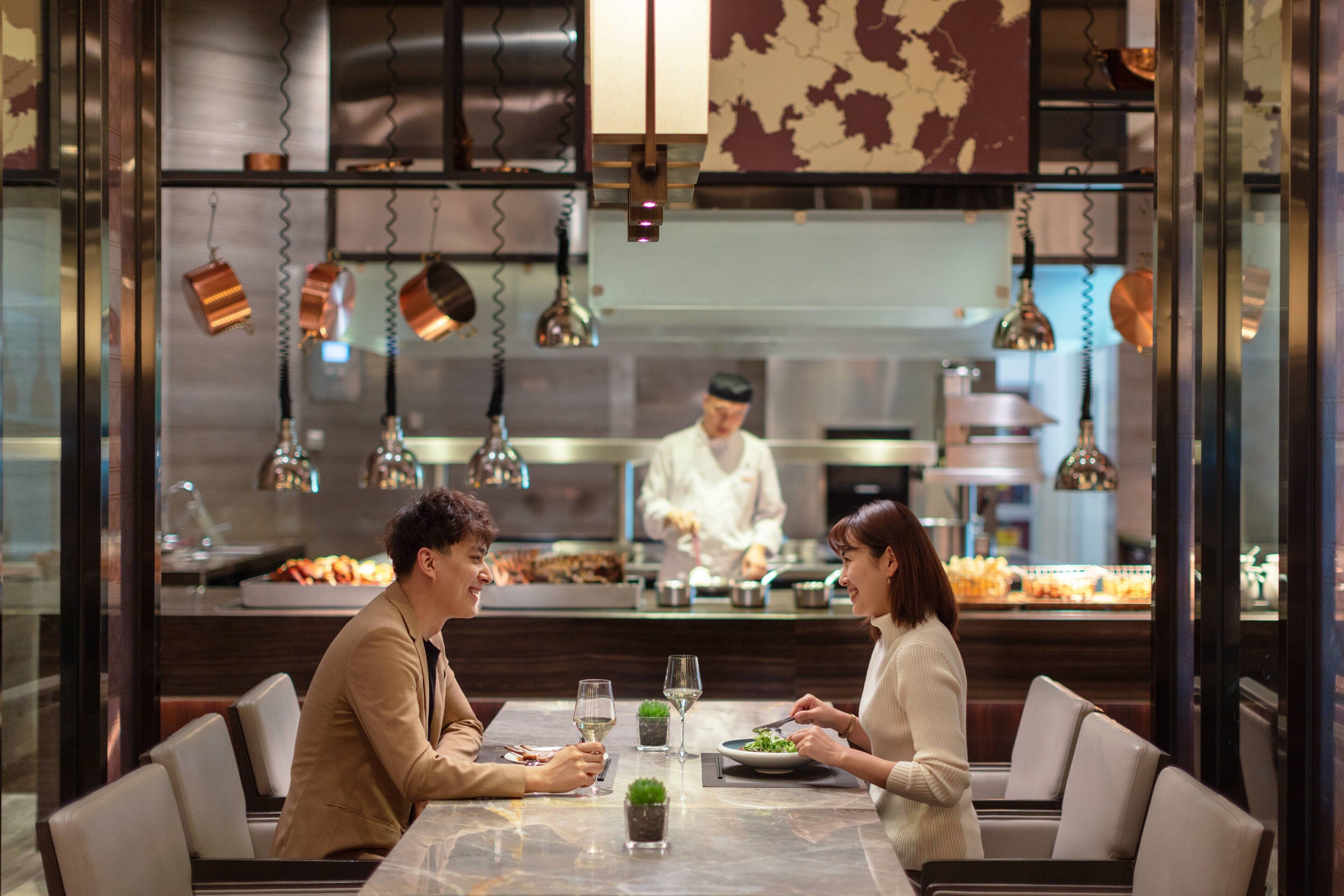 A dining area with a marble table, cushioned chairs, and hanging copper pots.