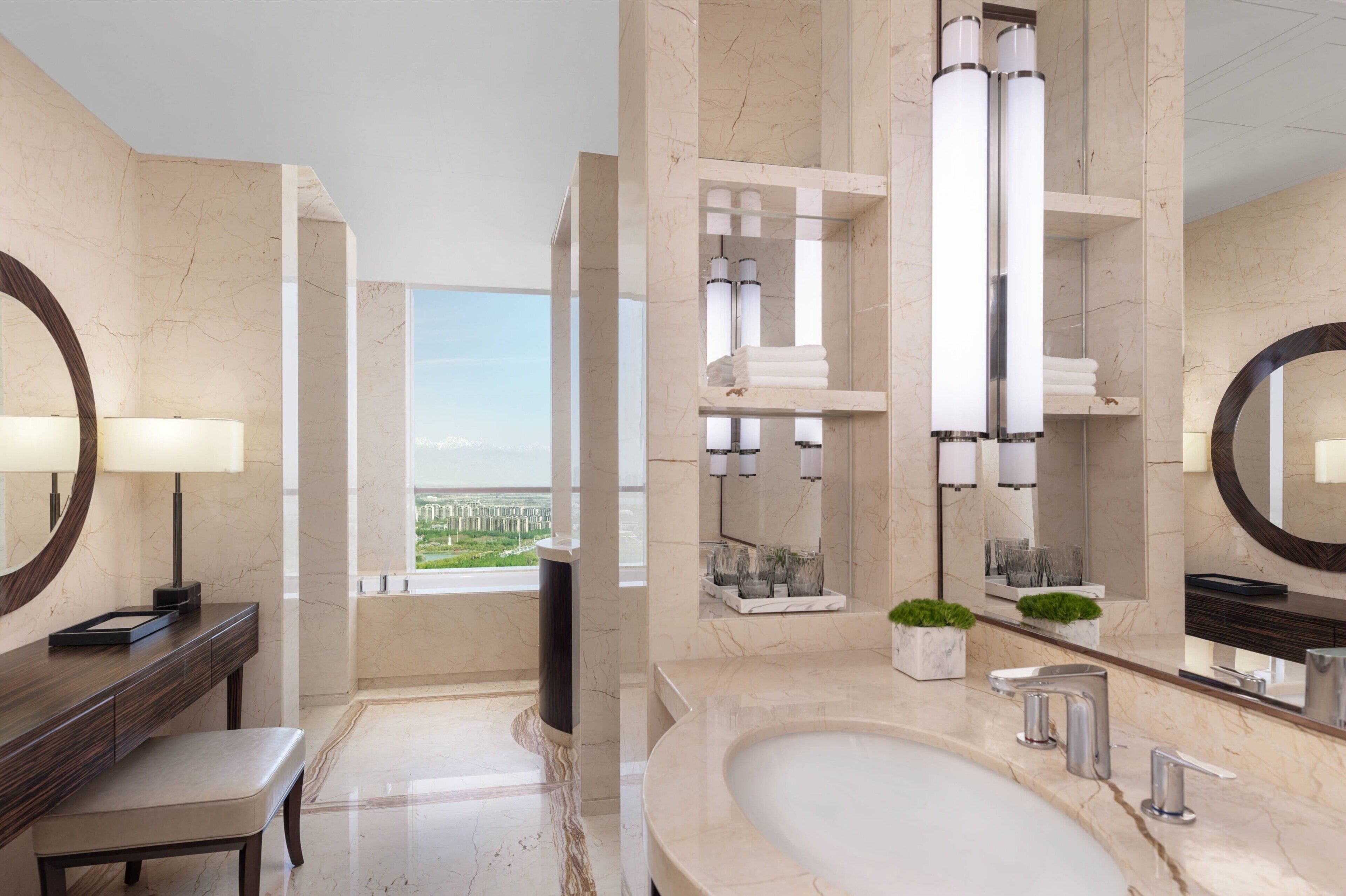 A modern bathroom with a large bathtub, a vanity with a mirror, and a view of a cityscape.