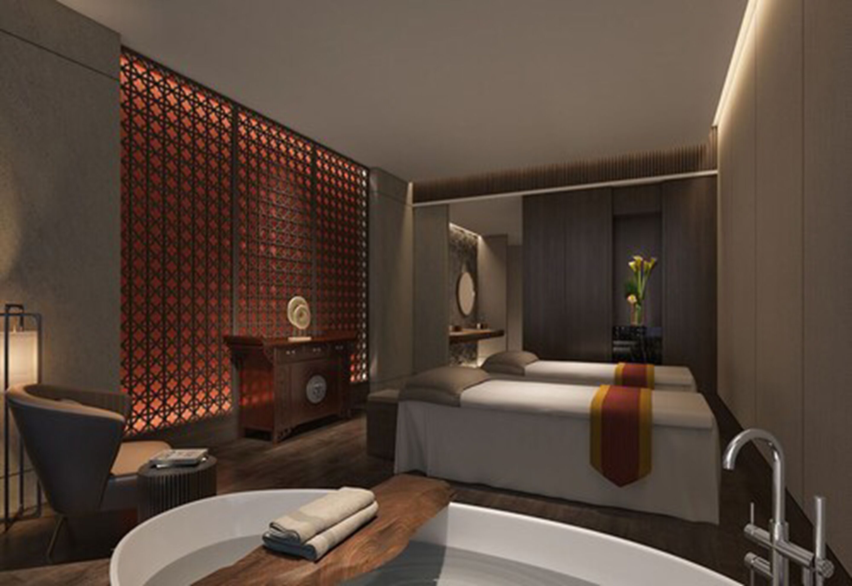 Una habitación de hotel moderna con una cama grande, una zona de estar con una silla y una mesita, un adorno en la pared y una bañera amplia.