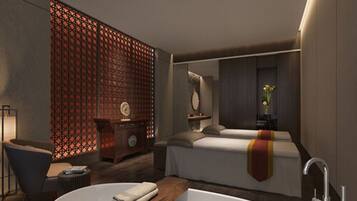 Una habitación de hotel moderna con una cama grande, una zona de estar con una silla y una mesita, un adorno en la pared y una bañera amplia.
