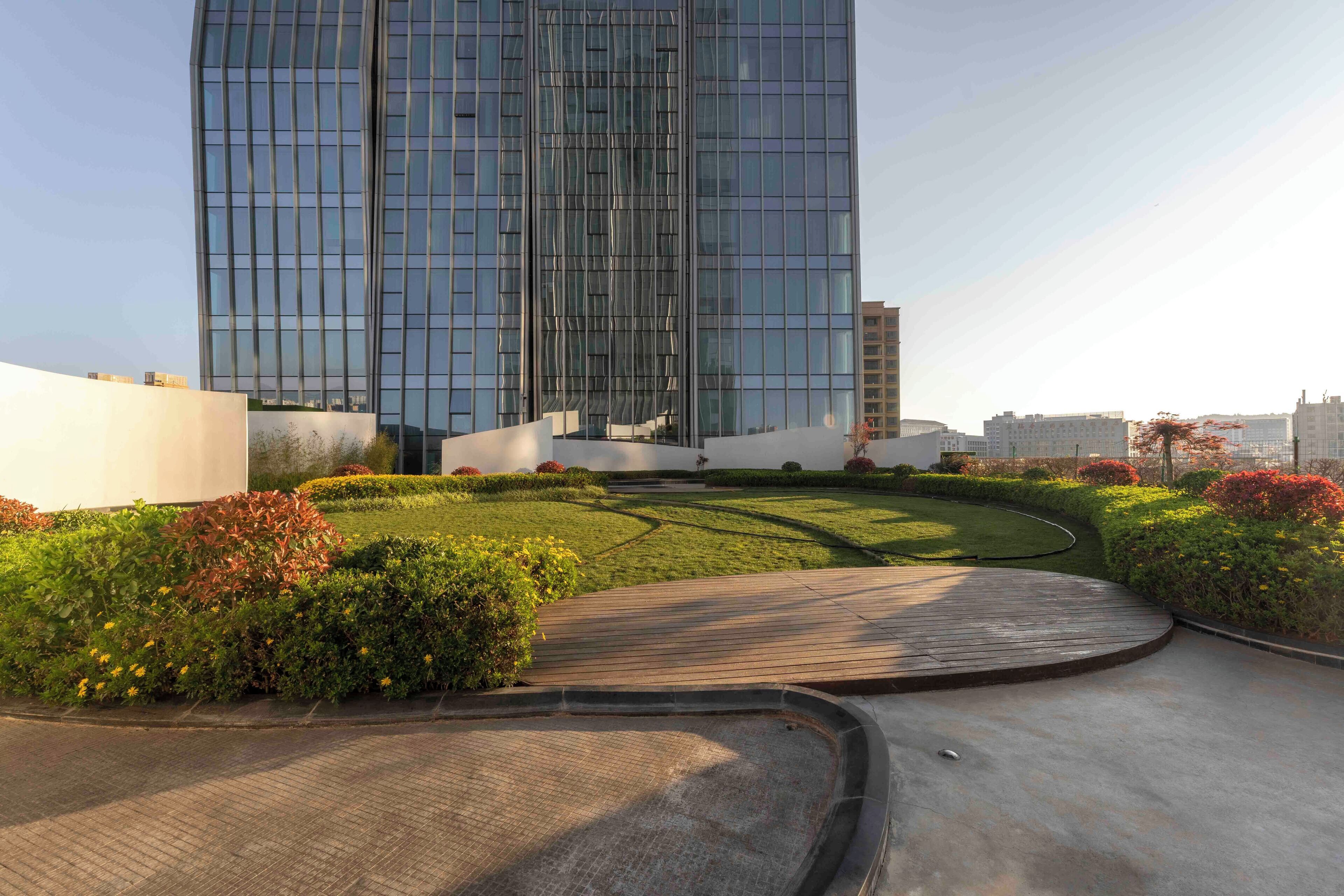 A modern building with a glass facade, surrounded by a landscaped garden with a curved pathway.