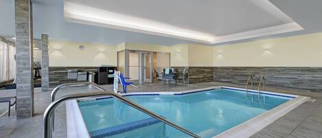 A modern indoor swimming pool with clear lane markings, a lifeguard chair, and a reception area with a counter and seating.