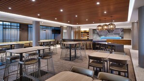 Uma zona de refeições moderna com mesas e cadeiras altas, um bar e uma área de estar com vista.