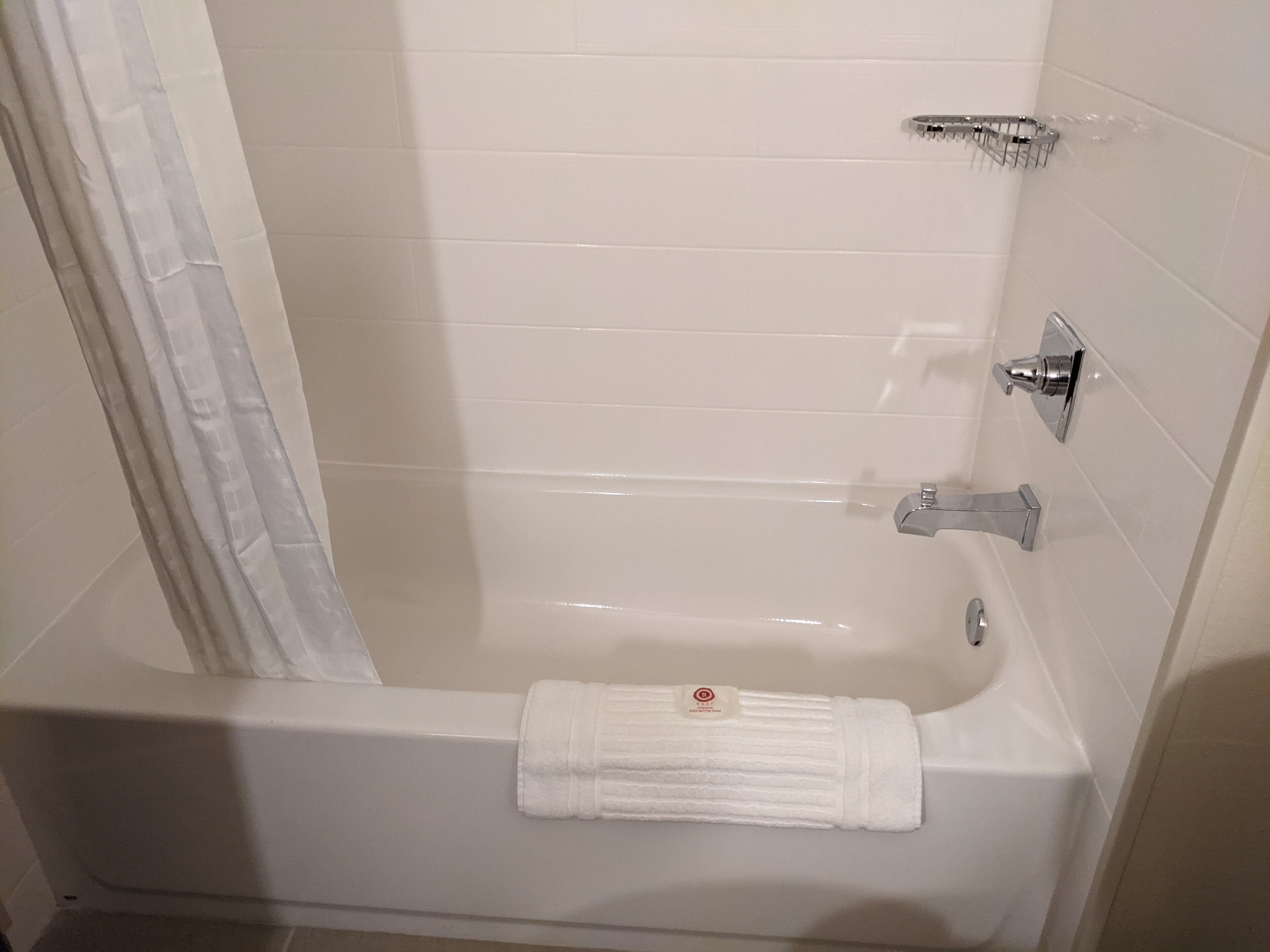 Un baño con bañera, toallero y cabezal de ducha.