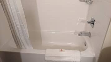 Un baño con bañera, toallero y cabezal de ducha.