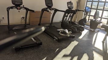 A home gym with treadmills, a stationary bike, and a rowing machine.