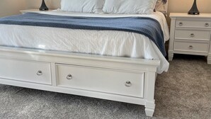 A bedroom with a white bed, two bedside tables, a window with a sign, and a carpeted floor. - ROUGH RIVER LAKE Hot Tub, Pool, Grill, Fire Pit, Party Garage  (Falls of Rough)
