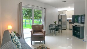 Ein modernes Wohnzimmer mit Sofa, Sessel und Essbereich mit Tisch und Stühlen.