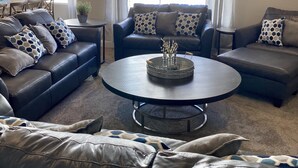 A modern living room with leather sofas, a glass coffee table, and a ceiling fan. - NEW🌟Spacious, Zion Village 7BD/6BA, Sleeps 32, Pool, Lazy River, View  (Hurricane)