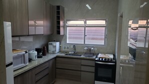 A compact kitchen with wooden cabinets, a microwave, a coffee maker, a toaster, and a stove.
