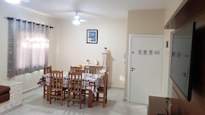 A dining area with a table set for six, wooden chairs, a ceiling fan, and a door with security signs.