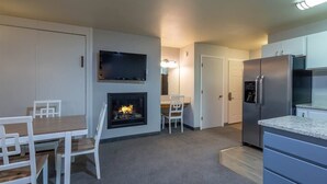 Une cuisine moderne dotée d’une cheminée intégrée, d’un coin repas avec une table et des chaises, et d’un réfrigérateur.