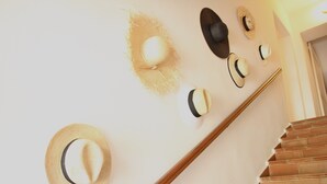 Una escalera con barandilla de madera y una pared decorada con varios sombreros.