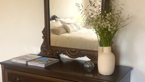 Un aparador de madera con un espejo, un florero con flores y un libro.