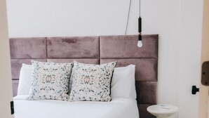 A bedroom with a bed, a headboard, a bedside table, and a checkered rug.