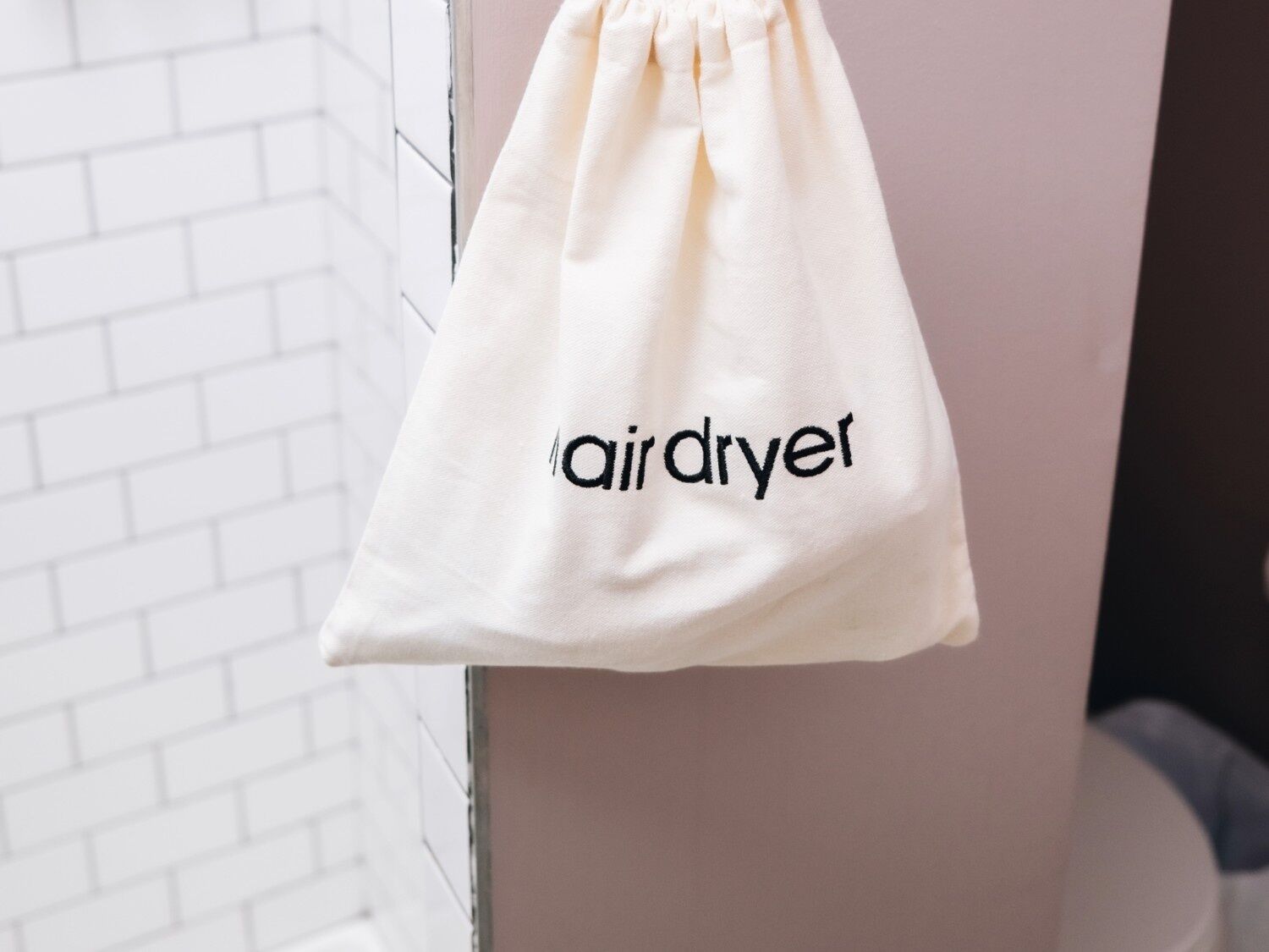 A white drawstring bag with the text 'airdryer' hanging on a wall.