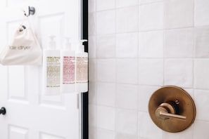 Un baño con una puerta blanca, un pomo de latón y una bolsa blanca colgada de la puerta.