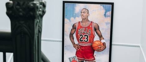 A framed portrait of a basketball player in a red jersey with the number 23, mounted on a white wall in a hallway.