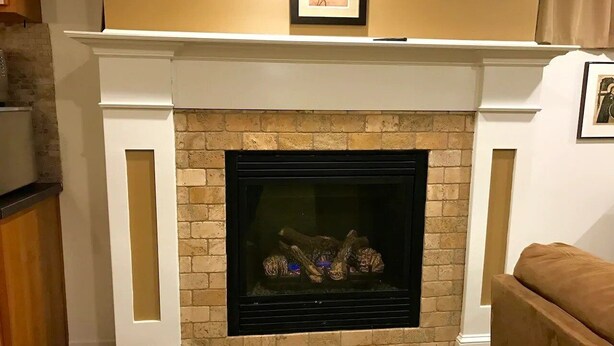 A fireplace with a brick surround, a white mantel, and a framed picture above it. - Comfortable Apartment in Northwest Omaha (Omaha)