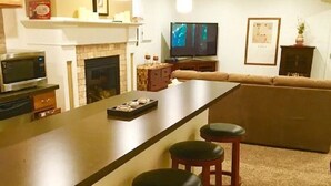 A modern kitchen with a bar area, a fireplace, and a television. - Comfortable Apartment in Northwest Omaha (Omaha)