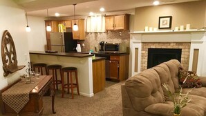 A living room with a sofa, a coffee table, and a dining area with a kitchen in the background. - Comfortable Apartment in Northwest Omaha (Omaha)