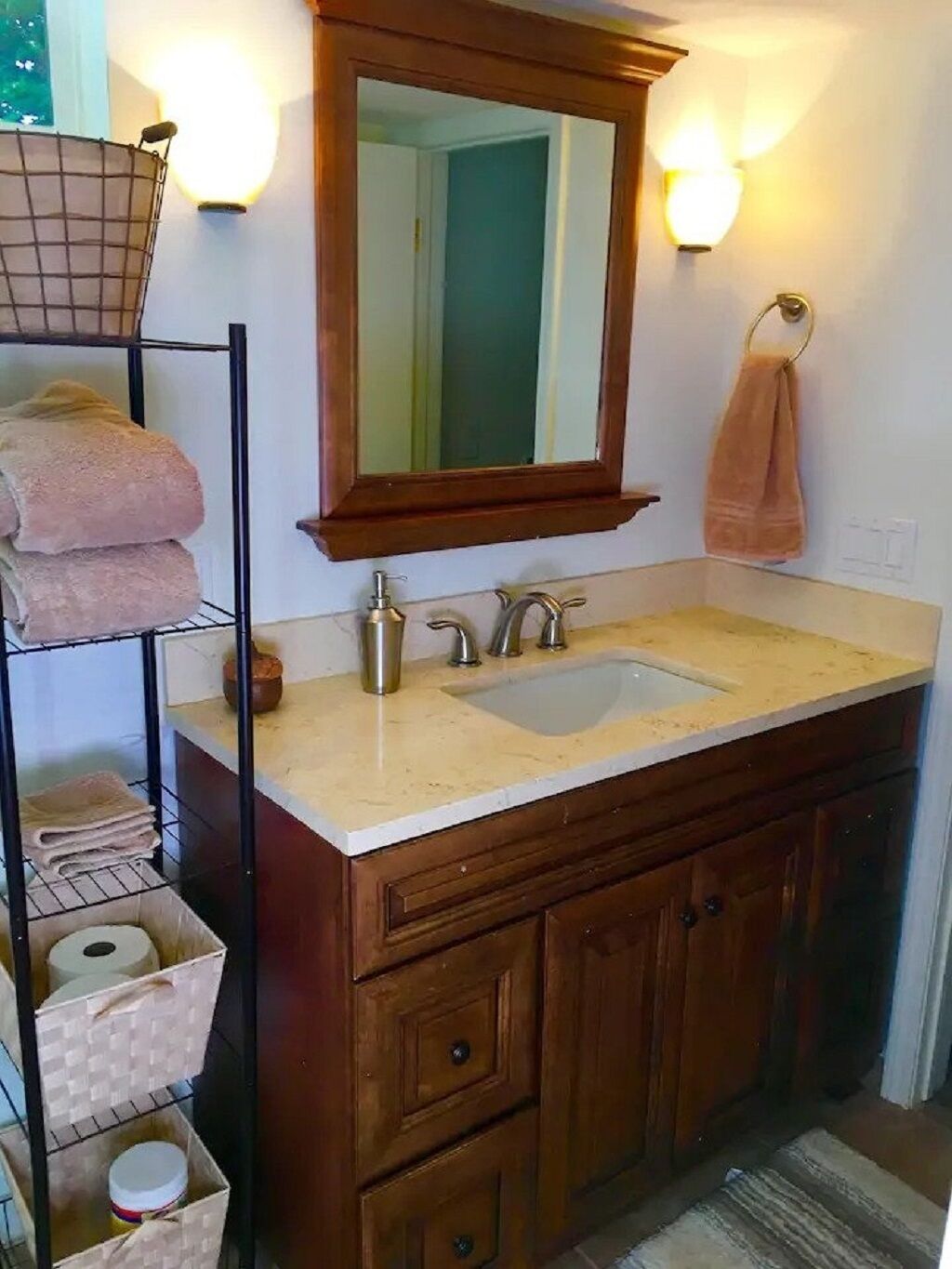 A bathroom with a wooden vanity, a double sink, a mirror, and a towel rack.