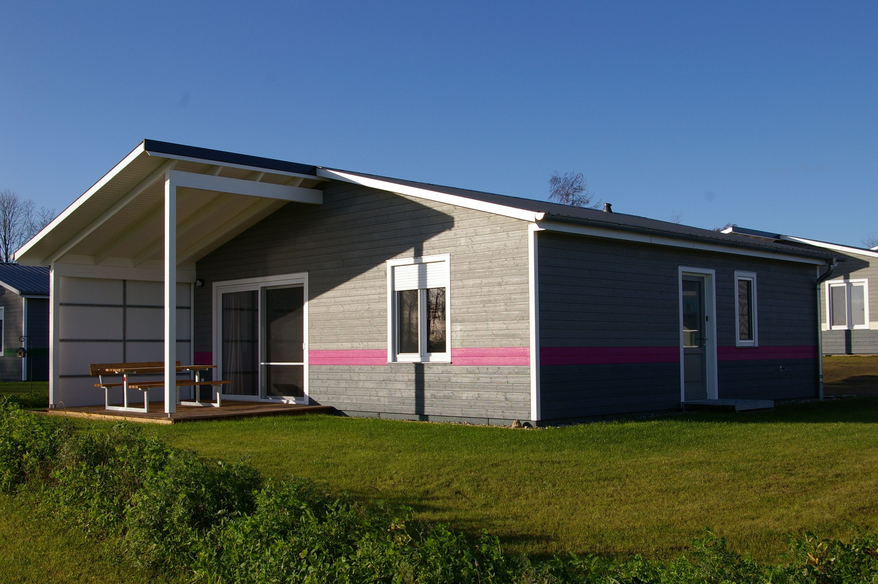 Un bâtiment moderne de plain-pied, doté d’un porche abrité et d’une porte donnant accès à un garage.