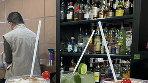 Three drinks on a bar counter with a shelf of liquor bottles in the background. - Posada Vista Tepoz (Tepoztlán)