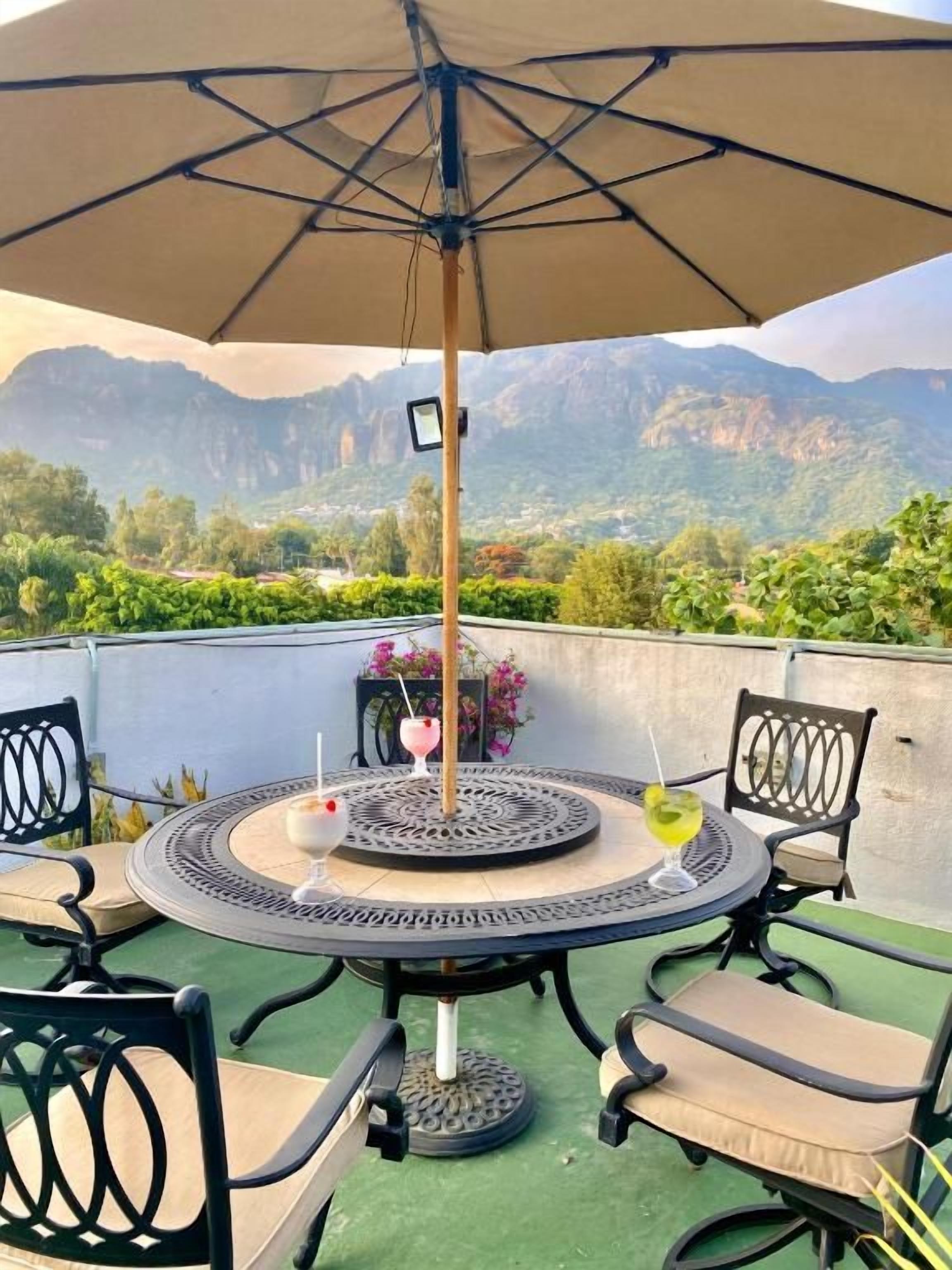 An outdoor patio with a round table, chairs, and a large umbrella.
