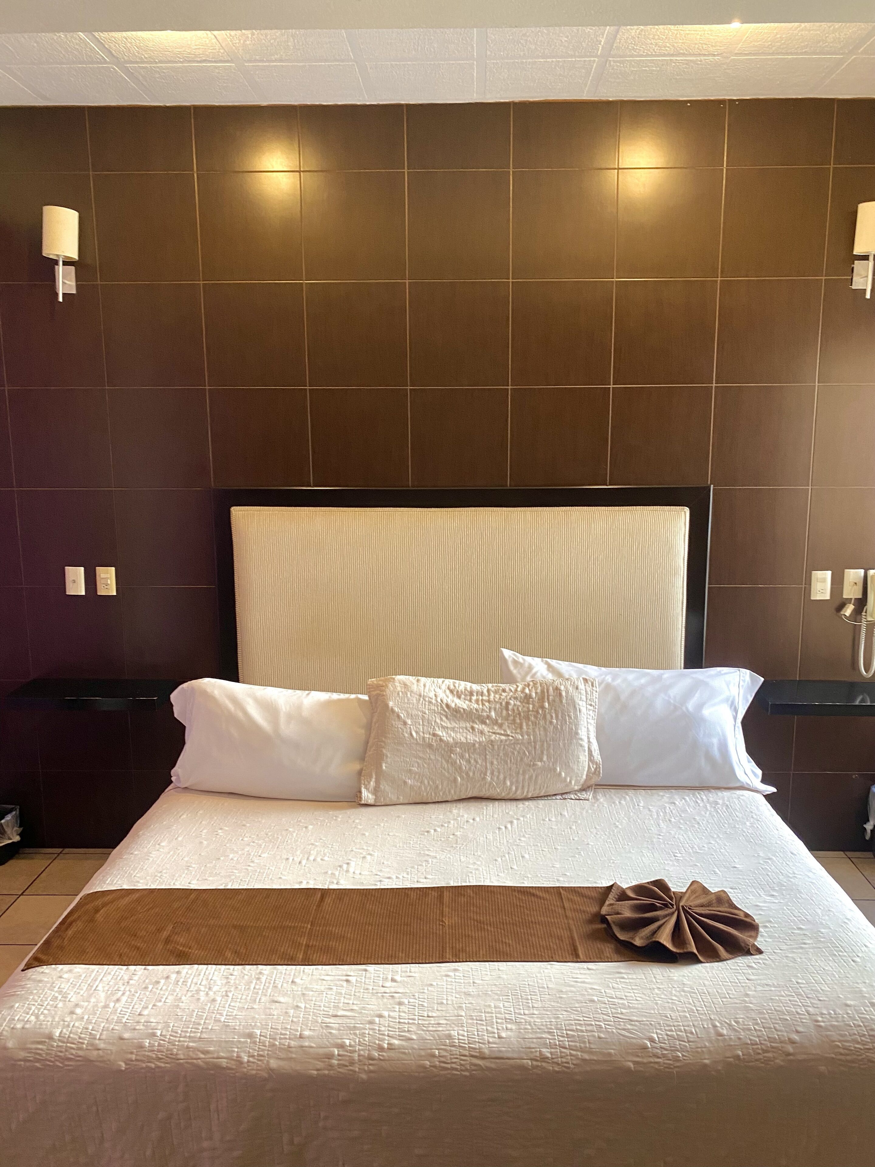 A hotel room with a large bed, two bedside tables, and a headboard.