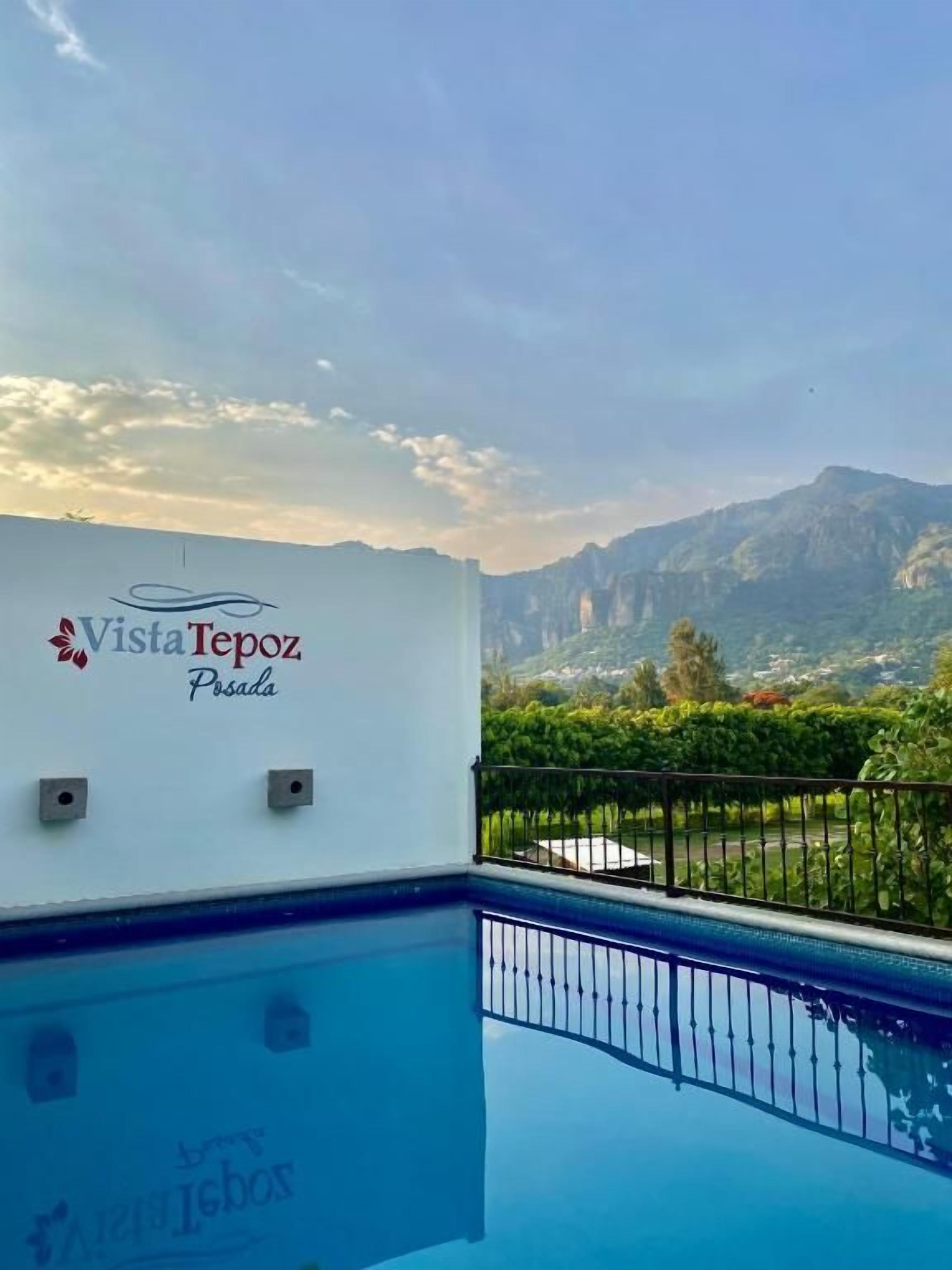 A swimming pool with a view of mountains and a white wall with the text 'Vista Tepoz Posada'.