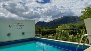 A swimming pool with a view of mountains and a cloudy sky. - Posada Vista Tepoz (Tepoztlán)