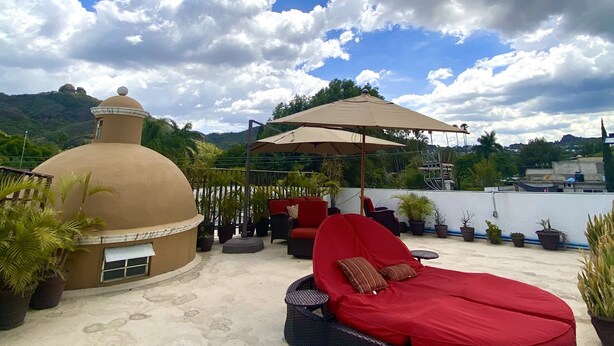 A rooftop terrace with a dome structure, red lounge chairs, and potted plants. - Posada Vista Tepoz (Tepoztlán)
